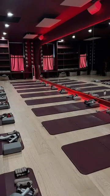 Pilates studio with rows of mats under pink lighting